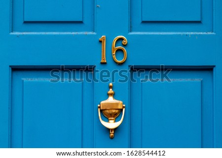 House number 16 on a blue wooden front door with door knocker