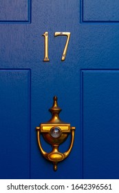 House Number 17 With Bronze Door Knocker On A Dark Blue Wooden Front Door