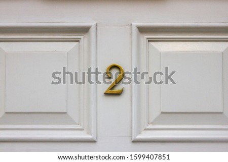 House number 2 on a white wooden front door with panels