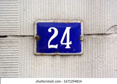 House Number 24 sign. Blue enamelled Number twenty-four plate mounted on a stucco wall.