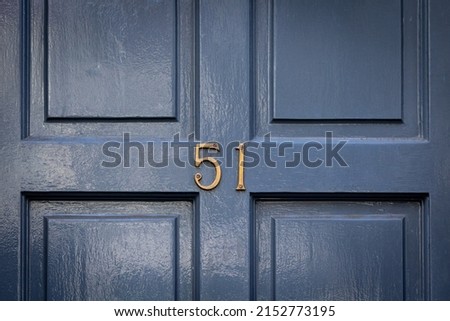 House number 51 on a blue wooden front door in golden metal digits