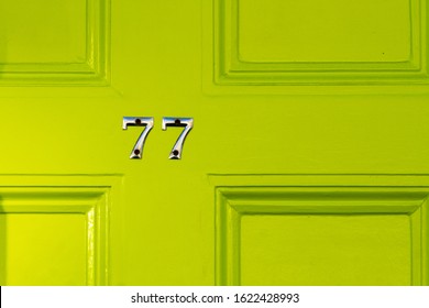 House Number 77 On A Lime Green Wooden Front Door