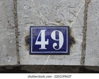 House Number (address) Forty Nine (49) Sign, White Numbered Blue Plate (closeup) Against Gray Wall Of 19th Century Old Building Background. Grunge, Texture, Wallpaper