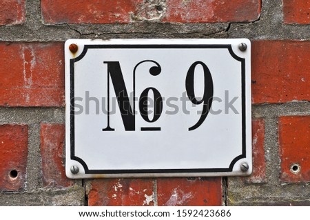 A house number plaque, showing the number nine (9)