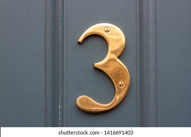 House Number Three With The 3 In Shiny Bronze Or Brass Metal On A Gray Front Door