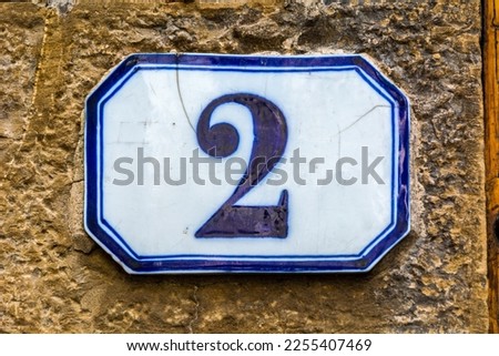 house number two ( 2 ) on a roughcast wall