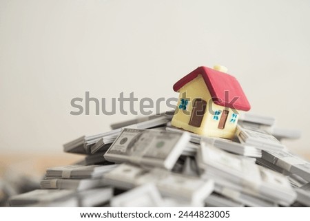 House on stack US dollar banknote with white wall background copy space. Banking, financial, mortagage loan concept. Central bank (FED) increase interest rates effect to house price and burden payment