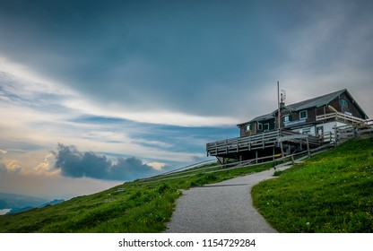 House On Top Of A Mountain With Clouds And Sunset On The Background