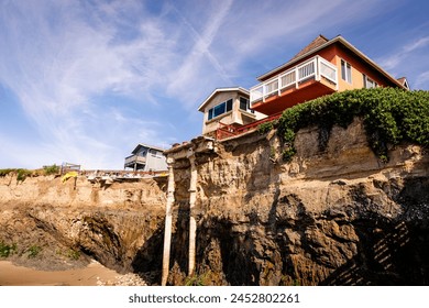 A house on top of a steep cliff overlooking the ocean, almost sliding into the ocean. Home of seaside bluff, almost falling down - Powered by Shutterstock