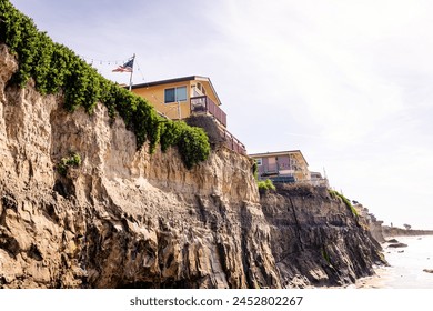 A house on top of a steep cliff overlooking the ocean, almost sliding into the ocean. Home of seaside bluff, almost falling down - Powered by Shutterstock