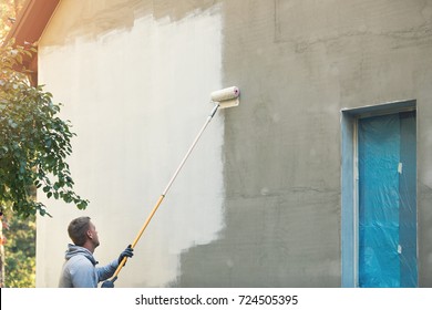 house painter painting building exterior with roller