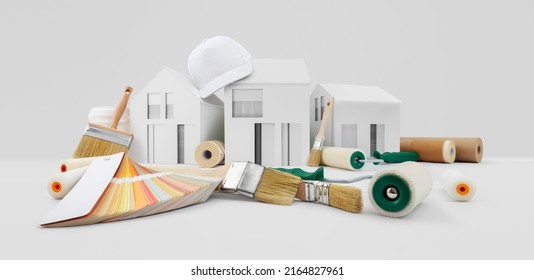 house painter tools, brushes, paint rollers, paper masking tape and colors swatches on desk with model house, supply and service in color shop in the hardware and store of building material.