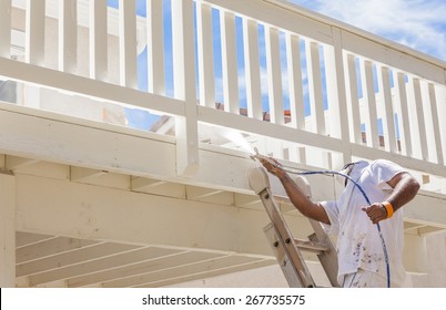 House Painter Wearing Facial Protection Spray Painting A Deck Of A Home.