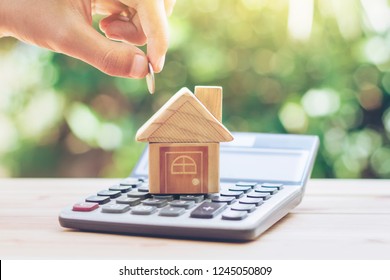 House is placed on the calculator. hand that is coin down the house. planning savings money of coins to buy a home concept for property, mortgage and real estate investment.to buy a house. - Shutterstock ID 1245050809