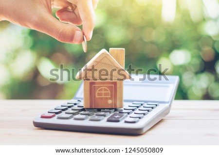 House is placed on the calculator. hand that is coin down the house. planning savings money of coins to buy a home concept for property, mortgage and real estate investment.to buy a house.