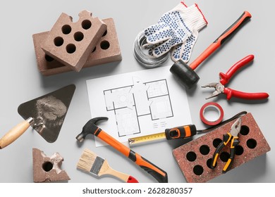 House plan, bricks and construction tools on grey background