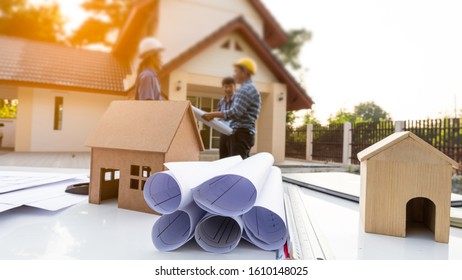 House Plan With Documents On The Table. Engineering Background. 3 People Standing.