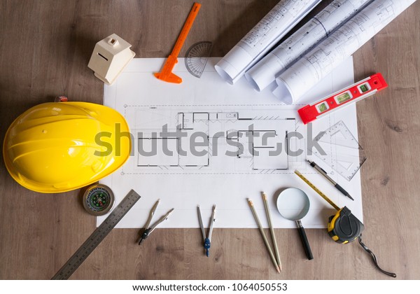 House plan\
with roll blueprints, ruler, dividers, pencil, security helmet and\
architect equipment on wooden\
background.