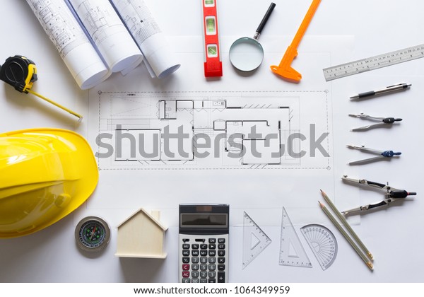 House plan with roll blueprints,\
ruler, dividers, pencil, security helmet and architect\
equipment
