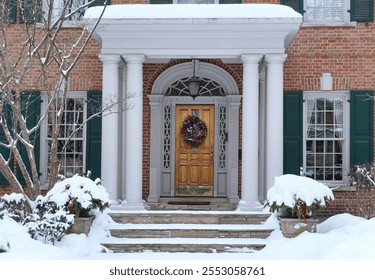 House with portico entrance and colorful Christmas wreath on wood grain front door