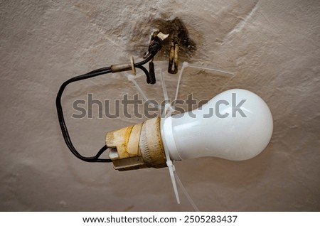 House problems, unsafe work concept. Photo of a lighting installation with an old ceramic light bulb socket improvised electrical wire connection