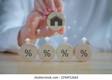 House and property investment and asset management concept. Interest rates, loan mortgage, house tax. Hand holding house icon on wooden circle from percent icon on wooden circle and rise of arrow. - Shutterstock ID 2196912663