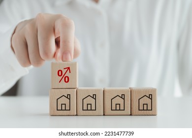 House, property investment, asset management concept. Interest rates increase, inflation, loan, mortgage, house tax, sale price. Hand touch red percentage sign icon on top of house icon on wood block. - Powered by Shutterstock - Get 15% off with code: PIKWIZARD15