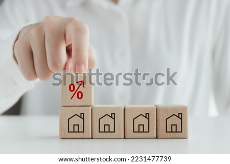 House, property investment, asset management concept. Interest rates increase, inflation, loan, mortgage, house tax, sale price. Hand touch red percentage sign icon on top of house icon on wood block.