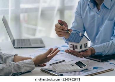 House purchase concept, real estate agent with house model talking to client about buying home insurance and client signing contract under formal contract agreement with real estate law - Powered by Shutterstock