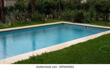 The House Rectangular Swimming Pool And Green Grass In The Backyard, In A Rainy Day. 	