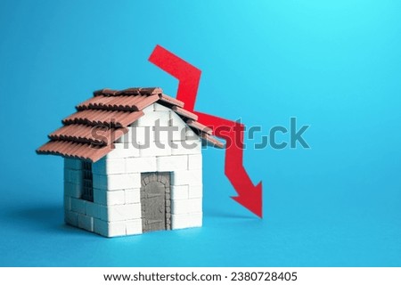 House and red arrow down. Falling housing prices. Unprofitability of investments, price fall in the real estate market. Lowering demand, construction rates and trends. Expensive mortgage.