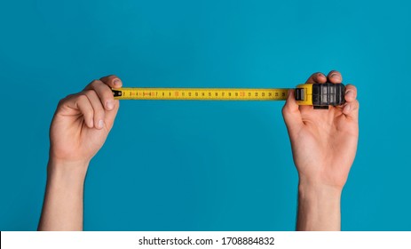 House renovation concept. Unrecognizable repairman holding tape measure on blue background, closeup. Panorama - Shutterstock ID 1708884832