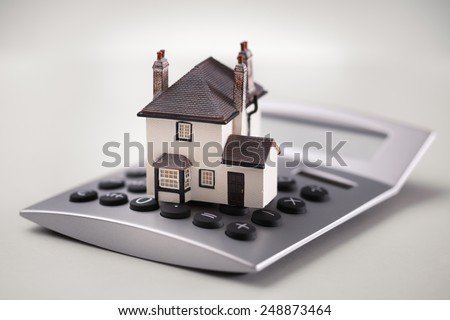 House resting on calculator concept for mortgage calculator, home finances or saving for a house