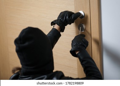 House Robbery By Woman In A Black Jacket And Black Mask. Burglar In A Mask. Thief In A Mask Trying To Break Into Other People's Apartments