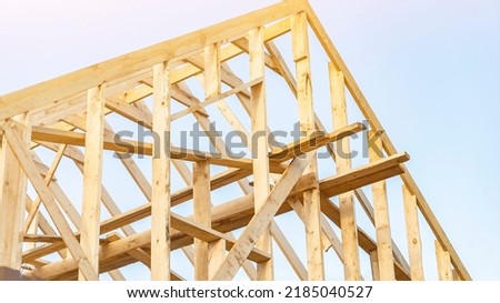 House roof carcass made of boards at construction site under blue sky low angle shot. Supporting frame of cottage. Natural materials benefits