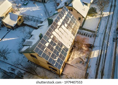 House Roof Covered With Solar Panels In Winter With Snow On Top. Energy Efficiency And Maintenance Concept.