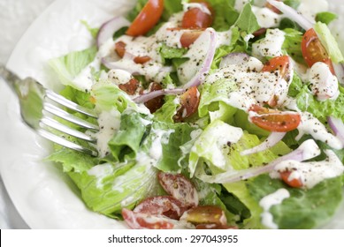 A House Salad Containing Leafy Greens, Grape Tomatoes, Red Onions, Ranch Dressing, And Fresh Cracked Black Pepper 