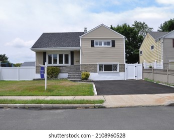 House For Sale Sign On Front Lawn Of Beige Suburban Snout Style Home In USA