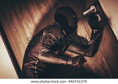 House Security Concept with Home Burglar in Action Trying To Break Into the House. 