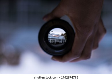 A house seen through the circular camera lens in a person's hand