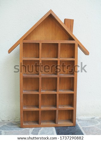 House shaped wooden shelf for showing dolls isolated on white wall.