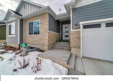 House With Snowy Yard And Steps Connecting The Front Door And Garage Door