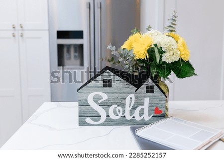 House Sold! Sign on bright kitchen counter with yellow flowers