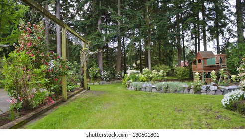 House Spring Backyard With Roses Patio And Kids Playground With Wooden Swing And Slide.