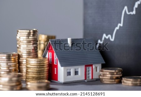 House with stacks of money and a rising curve symbolizing rising real estate prices