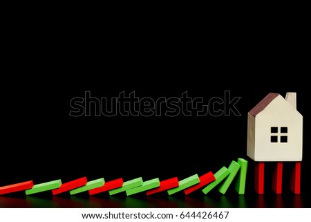 house standing on falling dominos on black background as a financial concept