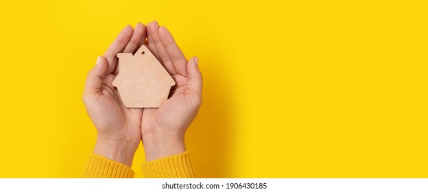 house toy in hands over yellow background, panoramic mock-up