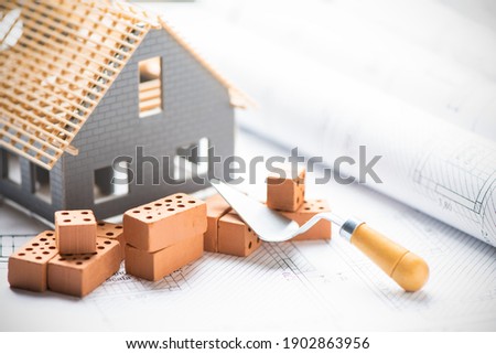 House under construction on blueprints close up. Building project concept