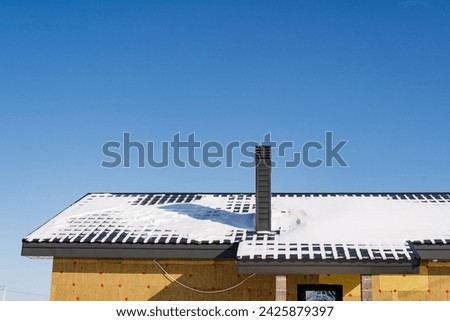 A house under construction with snow on the roof, the building material and composite materials form the facade. The windows and fixtures decorate the sky with a picturesque view