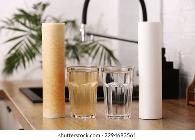 House water filtration system to drinkable condition. New clean water filter cartridge and glass of clear water. Used cartridge in rust and glass of dirty water on tabletop kitchen. World aqua day